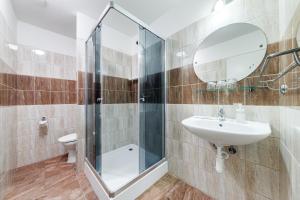 a bathroom with a shower and a sink and a mirror at Koruna Hotel in Prague