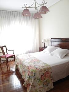 1 dormitorio con 1 cama con colcha de flores en Apartamento Tellería con parking gratis, en Barakaldo