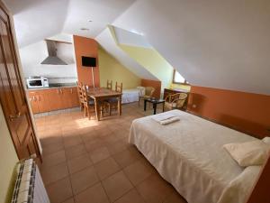 a bedroom with a bed and a table and a kitchen at Hostal El Horno in Molinaseca