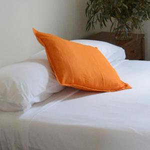 an orange pillow sitting on top of a white bed at Shamrock Hotel Motel Temora in Temora