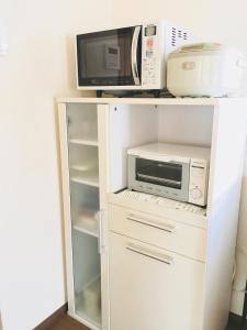 a white cabinet with a microwave and a refrigerator at ゲストハウス蘖 -ひこばえ in Kitakami