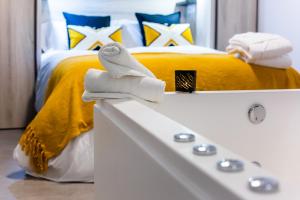 Apartamentos Hervás Suites في إرفاس: غرفة نوم بسرير اصفر وحوض استحمام ابيض