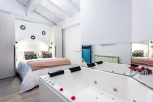 a bedroom with a bed and a bathtub with a mirror at Apartamentos Hervás Suites in Hervás