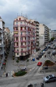 un gran edificio rosa en una calle de la ciudad con coches en Downtown Boutique Apartment en Tesalónica