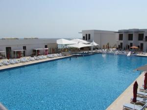 a large swimming pool with chairs and umbrellas at Mirage Bab Al Bahr Beach Resort in Dibba