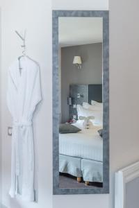 a mirror in a room with a bed and a robe at La Table de Gustave in Ornans