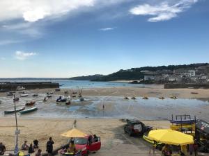 a beach with a group of people and cars on it at Modern studio apartment with stunning views! in St Ives