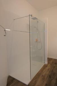 a glass shower in a room with a wooden floor at Maison d'hôtes Le 90 in Armentières