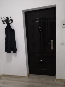 a black door with a coat hanging on a wall at Cosy Elegant Apartment in Cehu Silvaniei