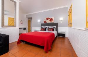 a bedroom with a large bed with a red blanket at Rosa dos Ventos in Zambujeira do Mar