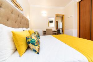 een slaapkamer met een groot wit bed met gele kussens bij Rosa dos Ventos in Zambujeira do Mar
