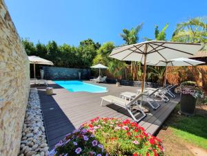 een patio met stoelen, een parasol en een zwembad bij SW1 Lodge in Somerset West