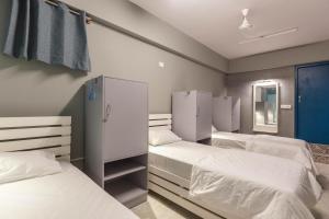 a bedroom with three beds and a mirror at Woke HSR layout in Bangalore