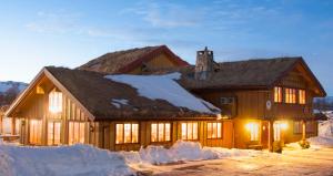 Hovden Fjellstoge في هوفدين: بيت خشبي كبير وحوله ثلج
