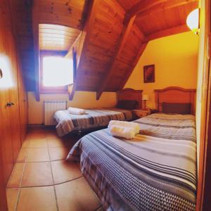 sypialnia z 2 łóżkami i drewnianym sufitem w obiekcie Apartamentos RUFASTE w mieście Salardú