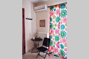 Zimmer mit einem Vorhang, einem Tisch und einem Stuhl in der Unterkunft Aloe apartment in Askeli in Poros