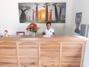 une femme debout derrière un bureau avec un vase de fleurs dans l'établissement Emeraude Lodge, à Andilana