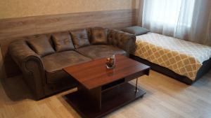 ein Wohnzimmer mit einem braunen Sofa und einem Tisch in der Unterkunft Sweet Apartments in Šiauliai