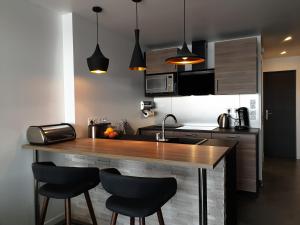 uma cozinha com um balcão de madeira e cadeiras pretas em Le Cap d'Agde NATURISTE Grand T2 de standing avec GARAGE em Cap d'Agde