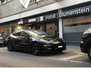 ein schwarzes Auto, das vor einem Laden parkt in der Unterkunft Hotel Blumenstein Self-Check In in Frauenfeld