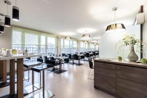 a dining room with tables and chairs and windows at Hotel Demas City in Munich