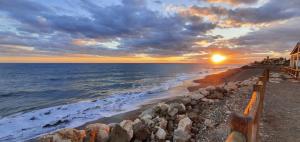 een zonsondergang boven de oceaan met een rotsachtig strand bij Suites Beach Nature by Alterhome in Vélez-Málaga