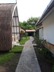 a path between two buildings with a thatch roof at Coco Bale in Gili Meno