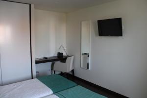 a bedroom with a bed and a desk with a monitor at Barquinha River House in Vila Nova da Barquinha