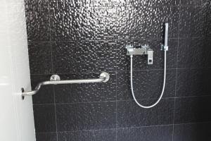 a shower in a bathroom with a black tiled wall at Barquinha River House in Vila Nova da Barquinha +38 photos