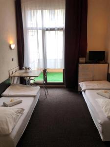 a room with two beds and a table and a window at Hotel Gryf in Gryfice