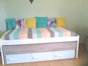 a bed with colorful blankets and pillows on it at le Boucanier in Tavira