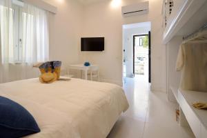 een witte slaapkamer met een bed en een televisie bij MARILISE - La maison blue private garden & terrace in Meta