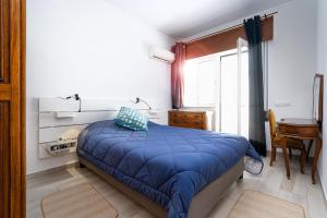 a bedroom with a bed with a blue comforter and a window at Casa Mina in Faro