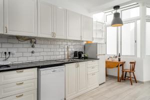 cocina blanca con armarios blancos y mesa en Casa Mina, en Faro