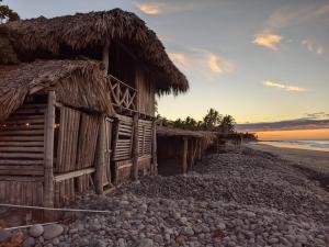 uma velha cabana na praia ao pôr do sol em Pelicano Surf Camp em La Libertad