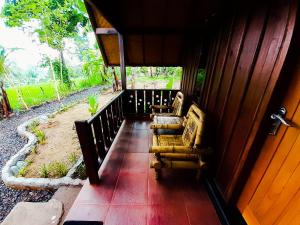 two chairs sitting on a porch of a house at Tetebatu Valley Bungalows in Tetebatu