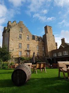 a large castle with a wooden barrel in the grass at Dornoch Castle Hotel in Dornoch