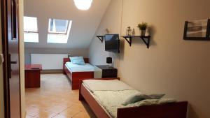 a small room with two beds and a tv at Pensjonat Morfeusz in Sianozety