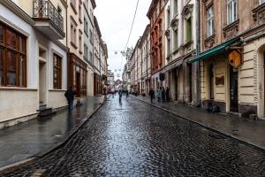 a cobblestone street with people walking down the street at Apartments in Rynok Square in Lviv