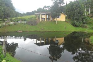 a house on a hill with a reflection in the water at Fazenda Monte Verde A Morada do Muriqui in São Francisco Xavier