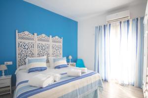 a blue bedroom with a bed with white pillows at Apartamentos Coso de San Albin in Merida