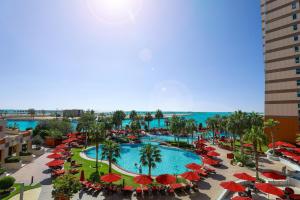 einen Luftblick auf einen Resortpool mit roten Sonnenschirmen in der Unterkunft Khalidiya Palace Rayhaan by Rotana, Abu Dhabi in Abu Dhabi