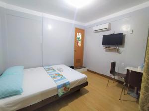 a bedroom with a bed and a desk and a tv at JB Valdres Apartment in Manila