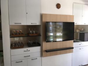 Il comprend une cuisine avec des placards blancs et une télévision à écran plat. dans l'établissement BANGALÔ PRAIA DE MURO ALTO/PORTO DE GALINHAS, à Porto de Galinhas