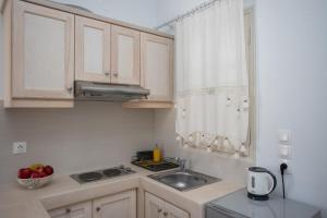 a kitchen with white cabinets and a sink and a window at Pansion Katerina in Skala