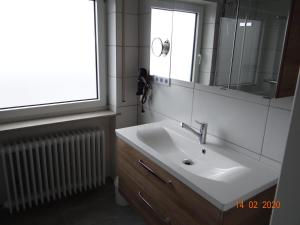 La salle de bains est pourvue d'un lavabo, d'un miroir et d'un radiateur. dans l'établissement Ferienwohnung Stein, à Verrenberg