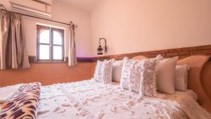 a bedroom with a bed with white pillows and a window at Riad Rihana Dades in Boumalne