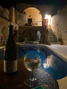 - une bouteille de vin et un verre à côté de la piscine dans l'établissement Warda Guest House, à Xewkija