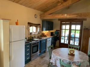 eine Küche mit einem Tisch und einem weißen Kühlschrank in der Unterkunft Gîte Le Pressoir in Cahuzac-sur-Vère