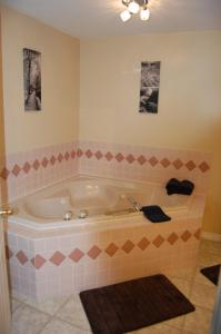 La salle de bains est pourvue d'une baignoire et de carrelage rose. dans l'établissement Monte Carlo Motel, à Barrière